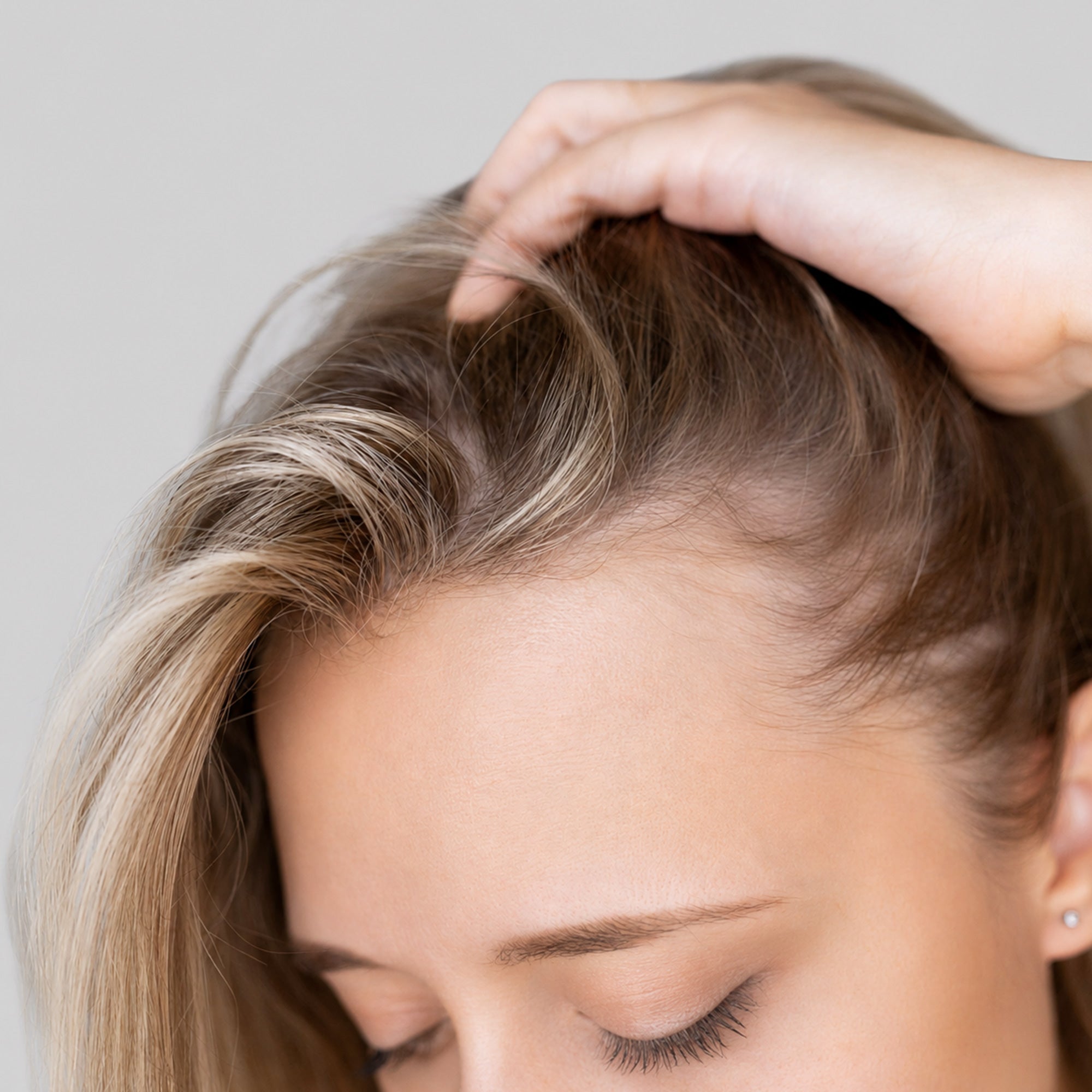 Donna con capelli biondi che tocca e sposta la chioma con le mani