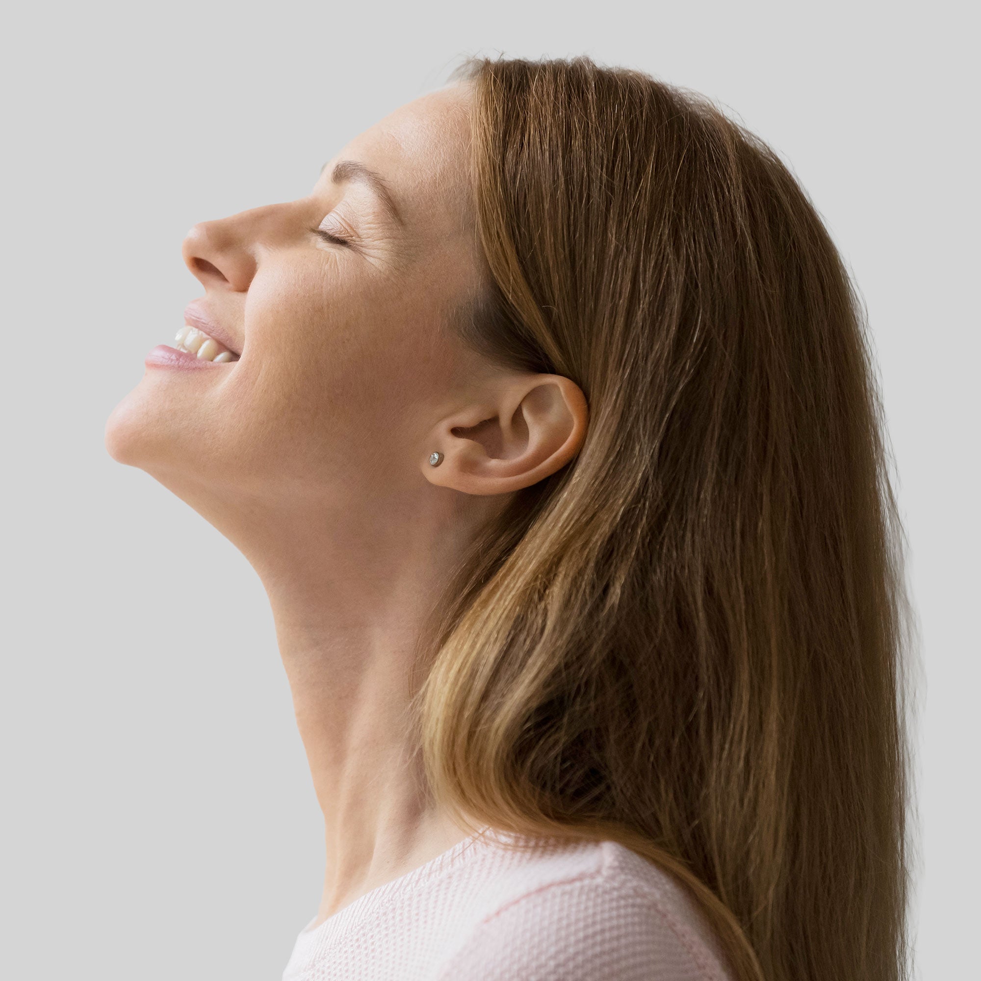 Donna di profilo che sorride mentre solleva lo sguardo, con dettagli dei capelli e del volto visibili