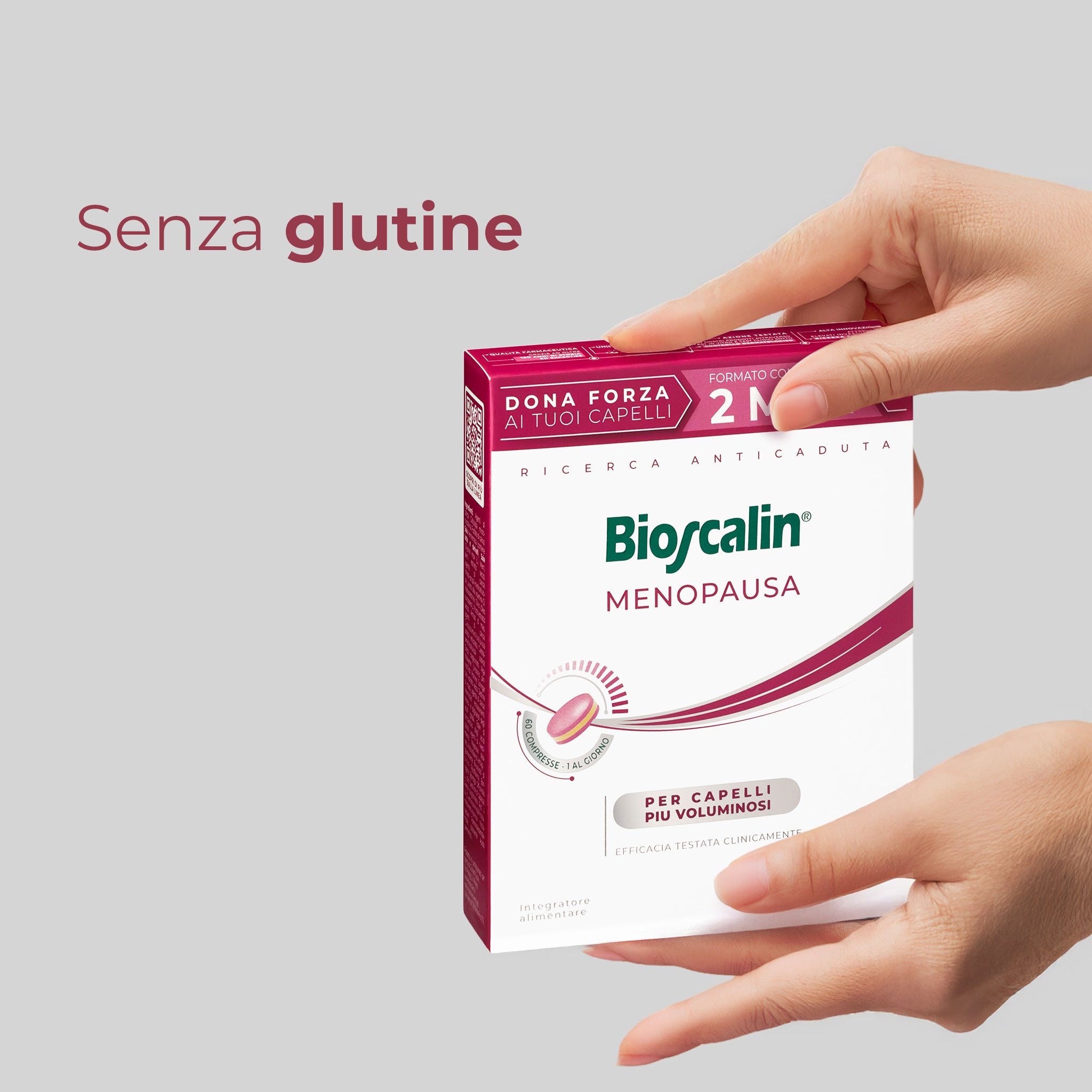 Primo piano di due mani che sorreggono una confezione di integratore Bioscalin® anticaduta per capelli linea Menopausa da 60 compresse