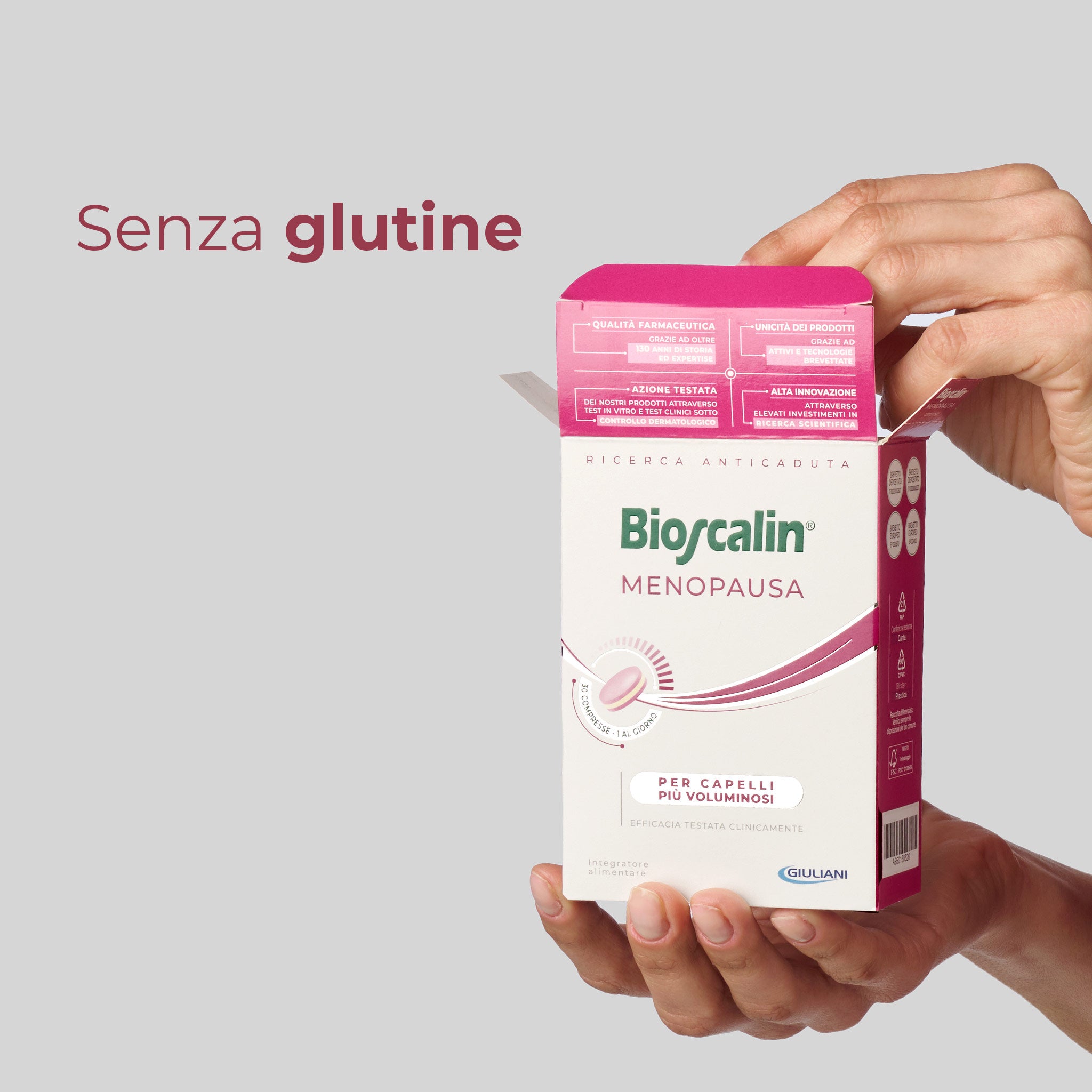 Primo piano di due mani che sorreggono una confezione di integratore Bioscalin® anticaduta per capelli linea Menopausa da 30 compresse