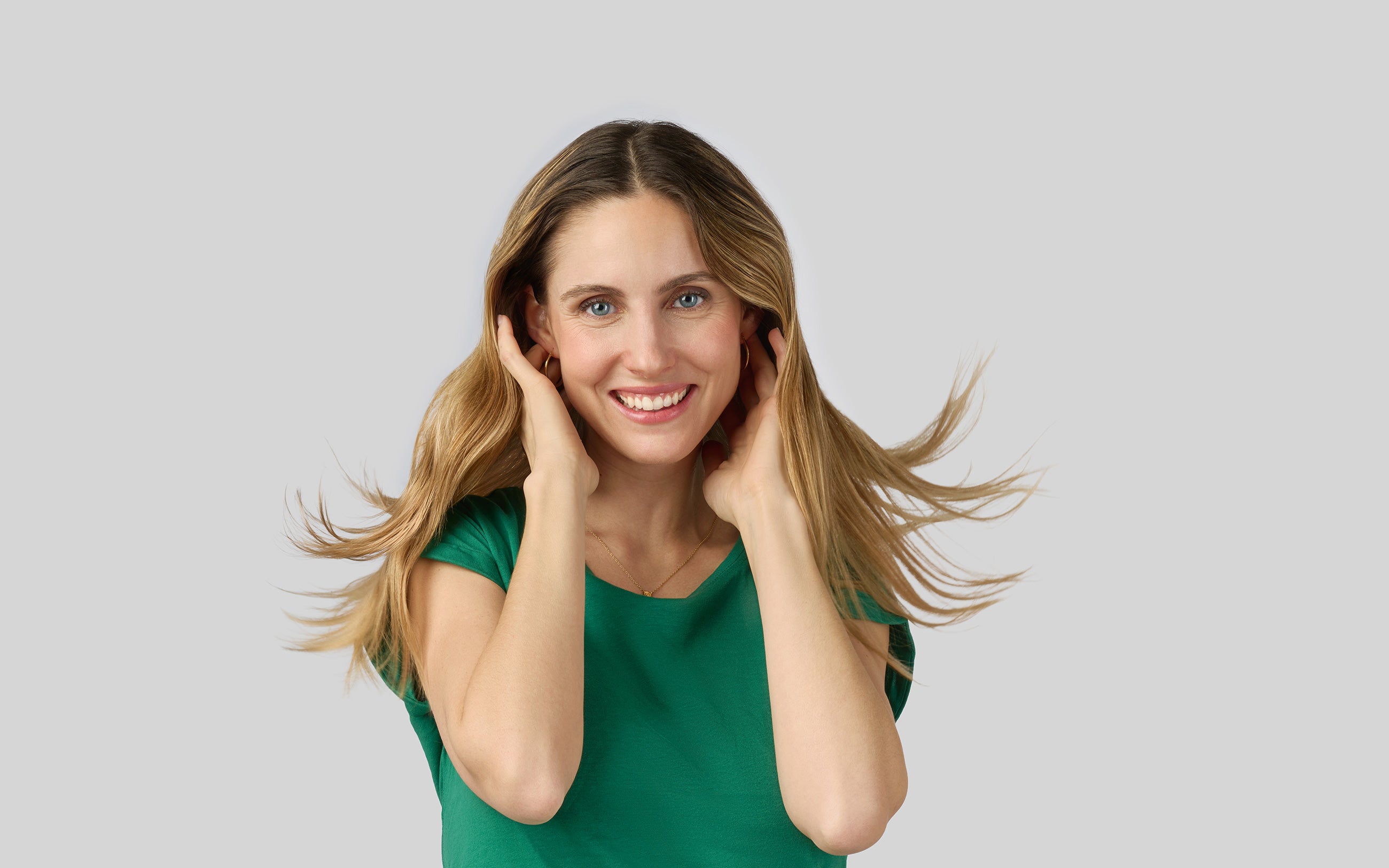 Donna con capelli lunghi e lisci sollevati leggermente dalle mani