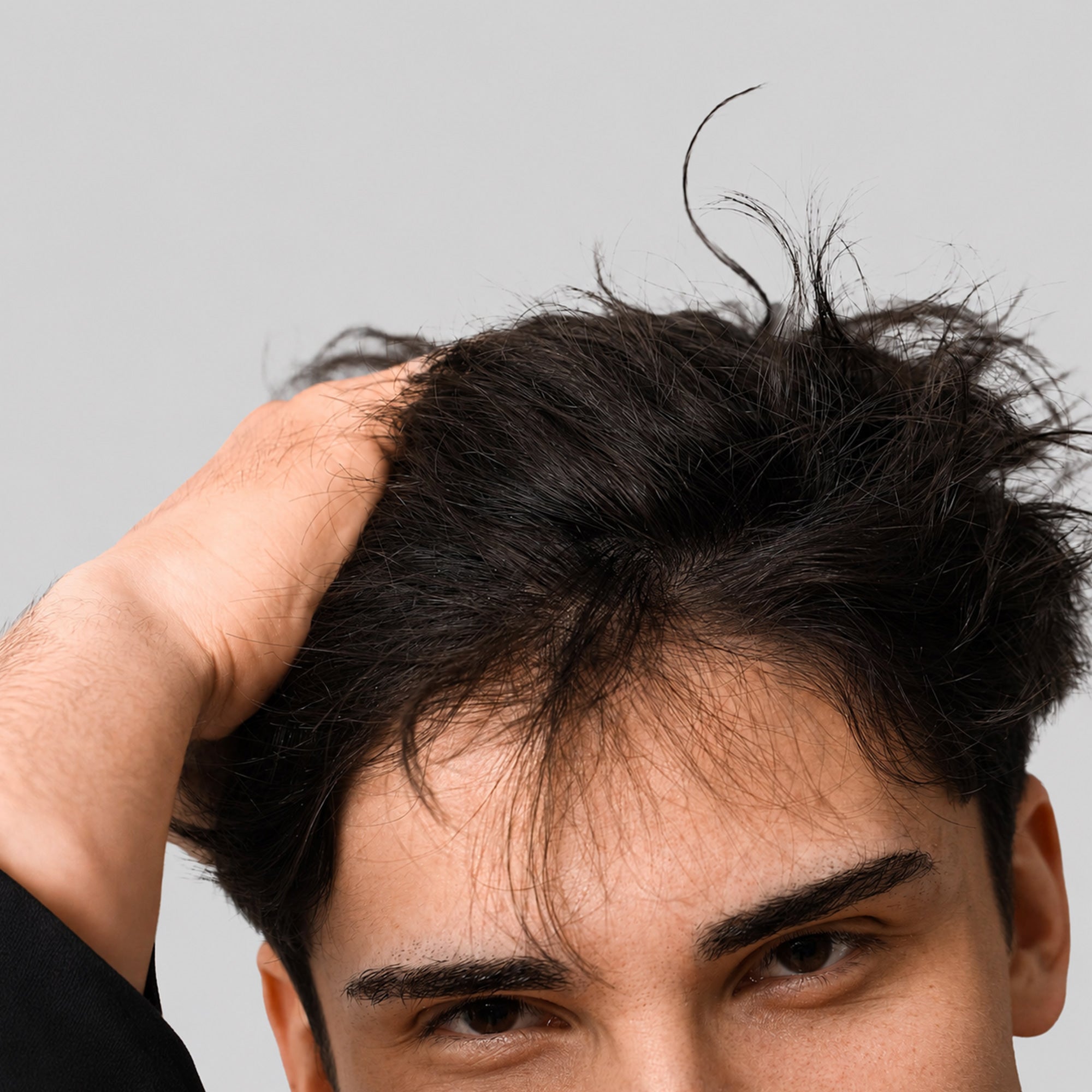 Uomo che si sposta i capelli per controllare la densità della chioma e l’attaccatura, possibile segnale di caduta dei capelli