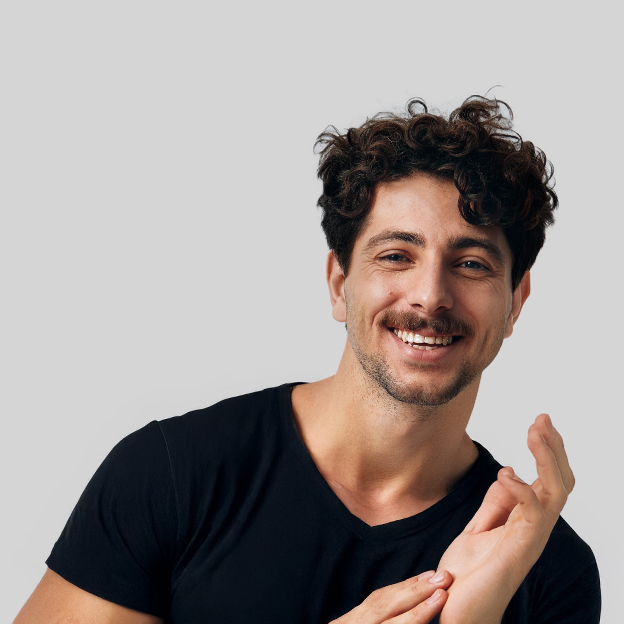 Uomo sorridente con capelli ricci: il supporto ed i consigli degli esperti Bioscalin® per la salute della tua chioma