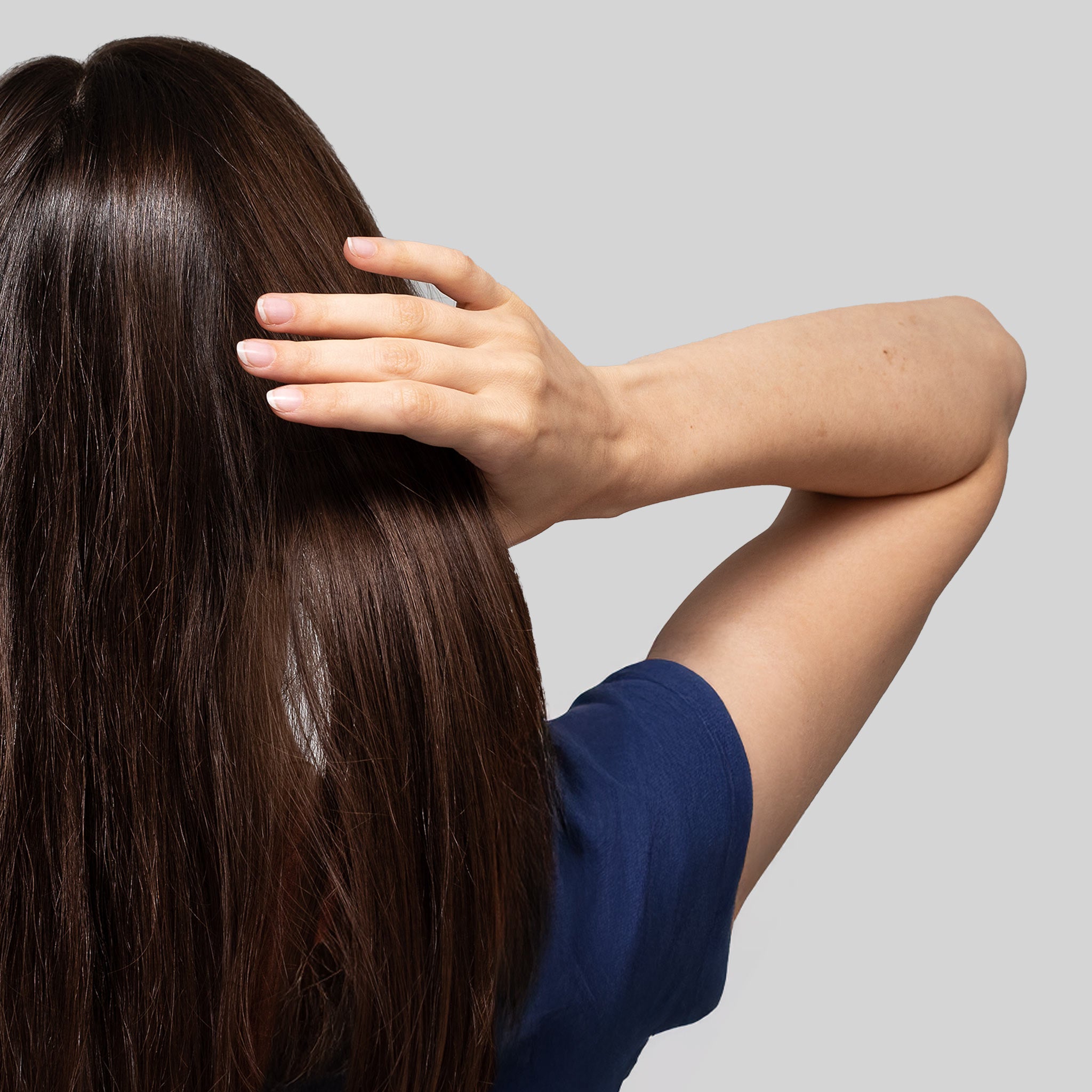 Donna che passa la mano tra i capelli folti: trattamento antiforfora Bioscalin® per un cuoio capelluto sano