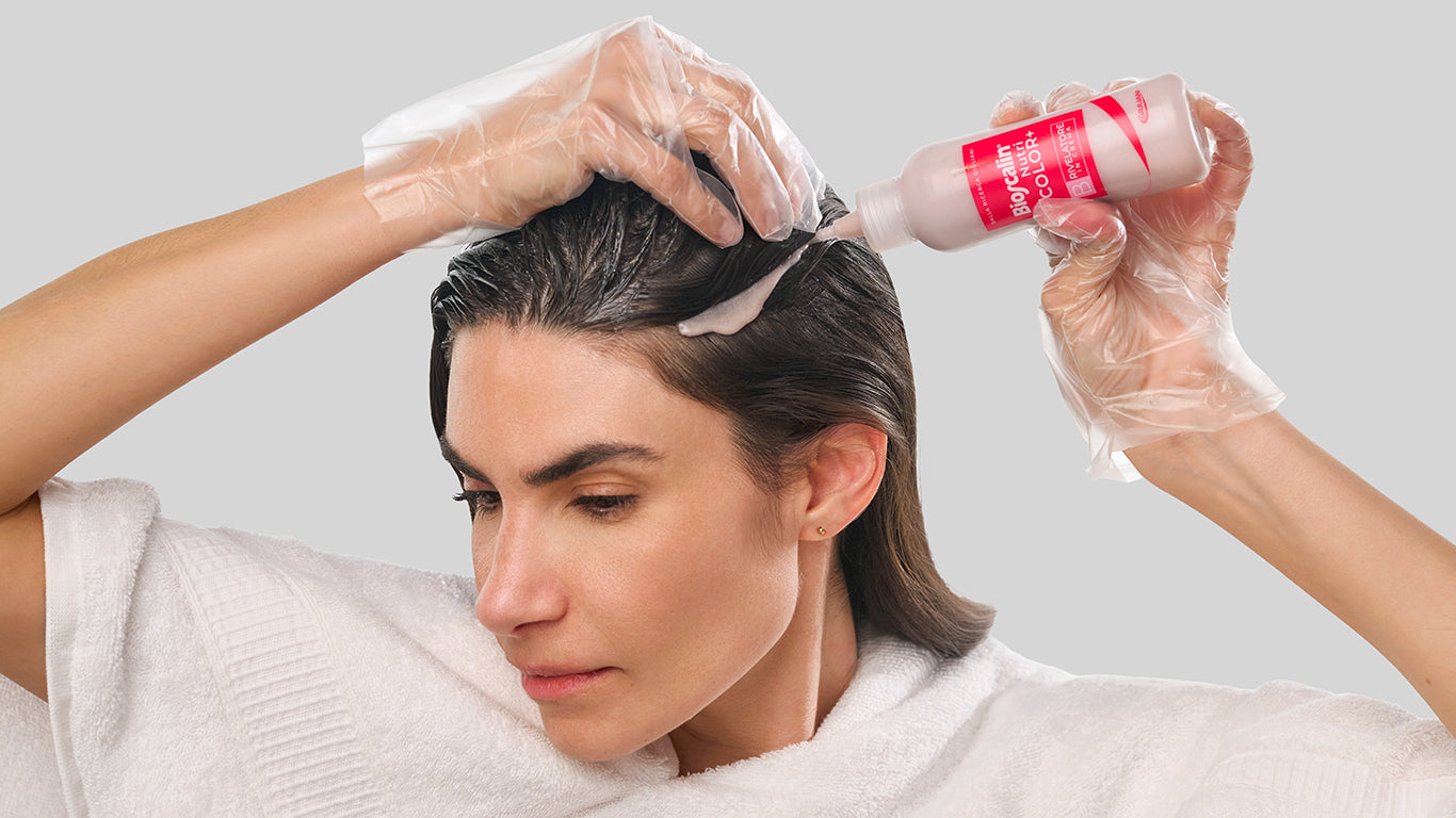 Donna che mostra come applicare la tinta NutriCOLOR+ Bioscalin® sui capelli bagnati