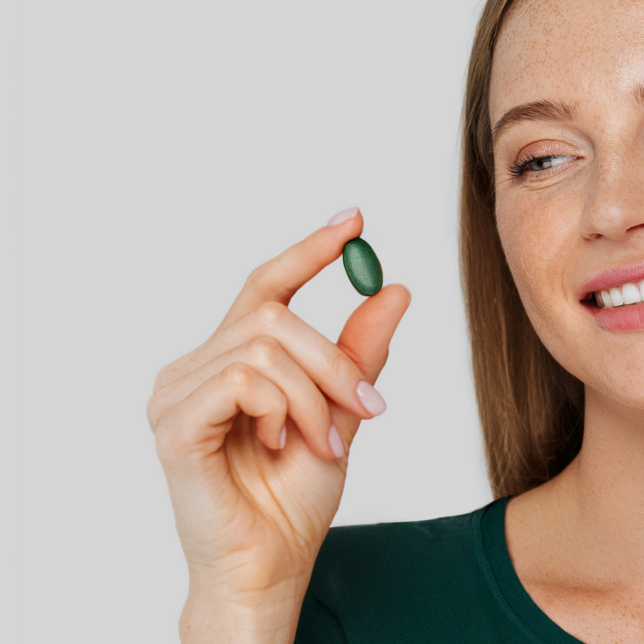 Mano che tiene una compressa verde Bioscalin®: integratore alimentare per il benessere dei capelli