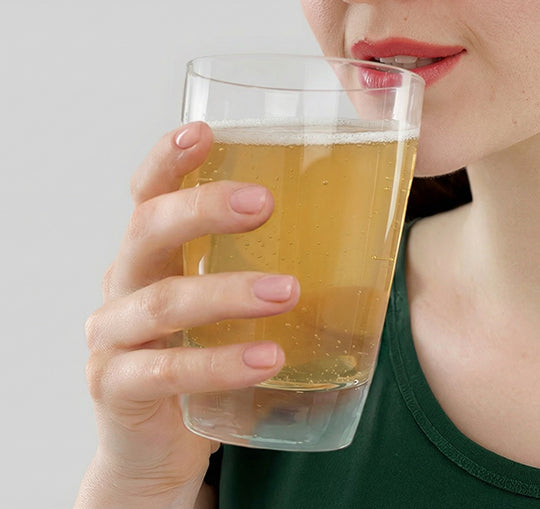 Primo piano di una donna che beve dal bicchiere in cui è stata sciolta una dose di Bioscalin® TOTAL•CARE in bustine