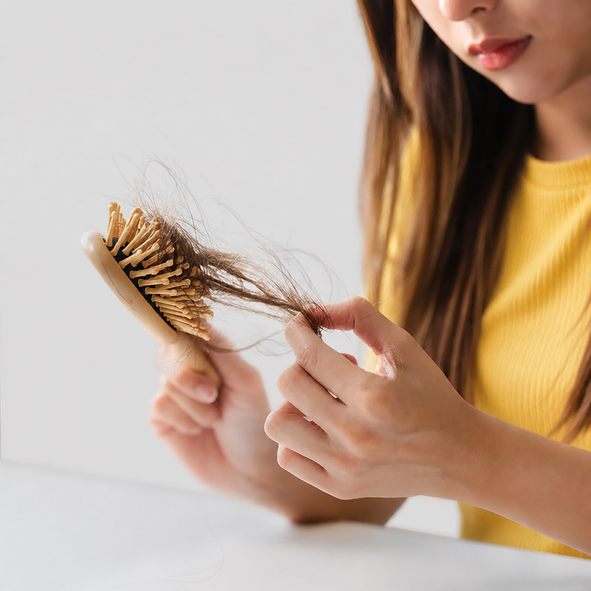 Donna che guarda con attenzione i capelli rimasti sulla spazzola dopo averli pettinati