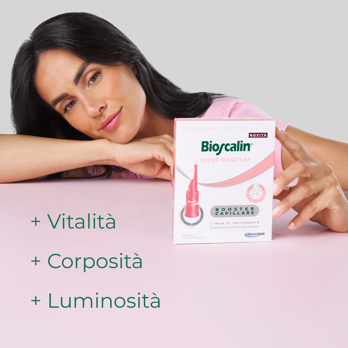 Donna accanto alla confezione del Booster Capillare Bioscalin® Post•Partum che dona vitalità, corposità e luminosità ai capelli.