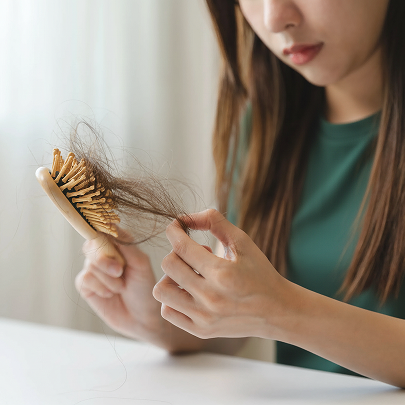 Donna che osserva la caduta dei suoi capelli sopra la spazzola dopo essersi pettinata 