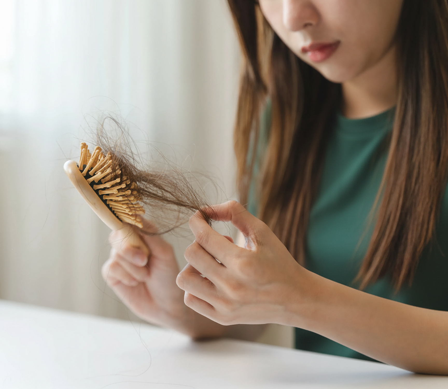 Donna che osserva i suoi capelli caduti sulla spazzola dopo essersi pettinata