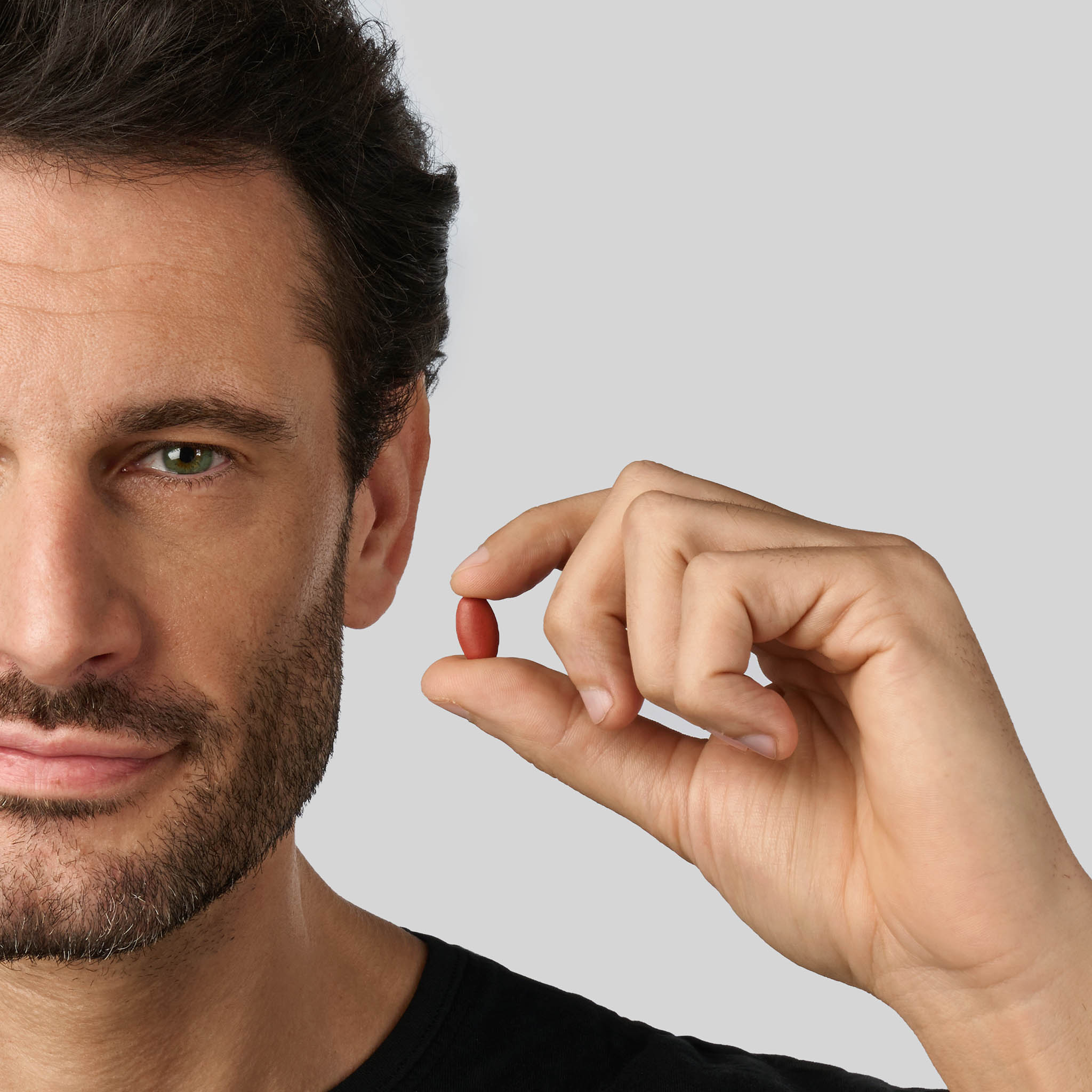 Uomo che tiene una compressa Bioscalin® specifica per la caduta dei capelli maschile