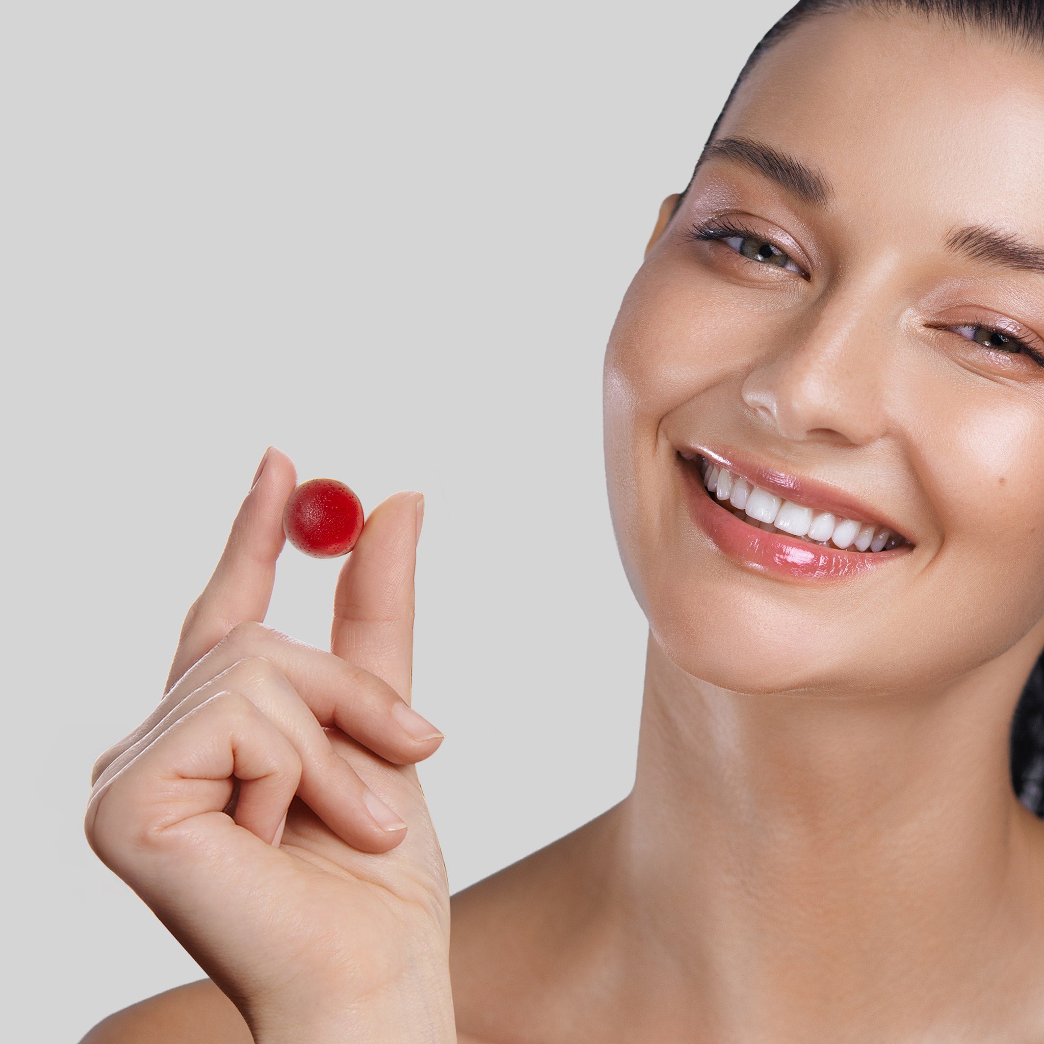 Donna sorridente che tiene una gommosa rossa Bioscalin® per contrastare la caduta temporanea